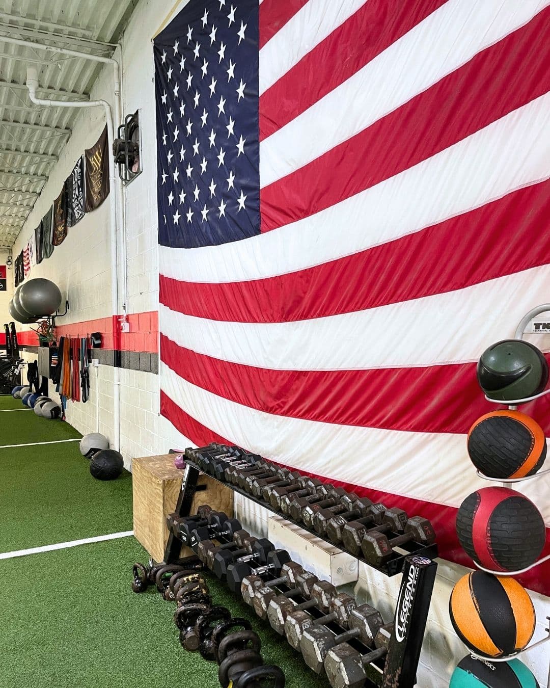 American flag and medicine balls in turf training area at AIM Performance Training