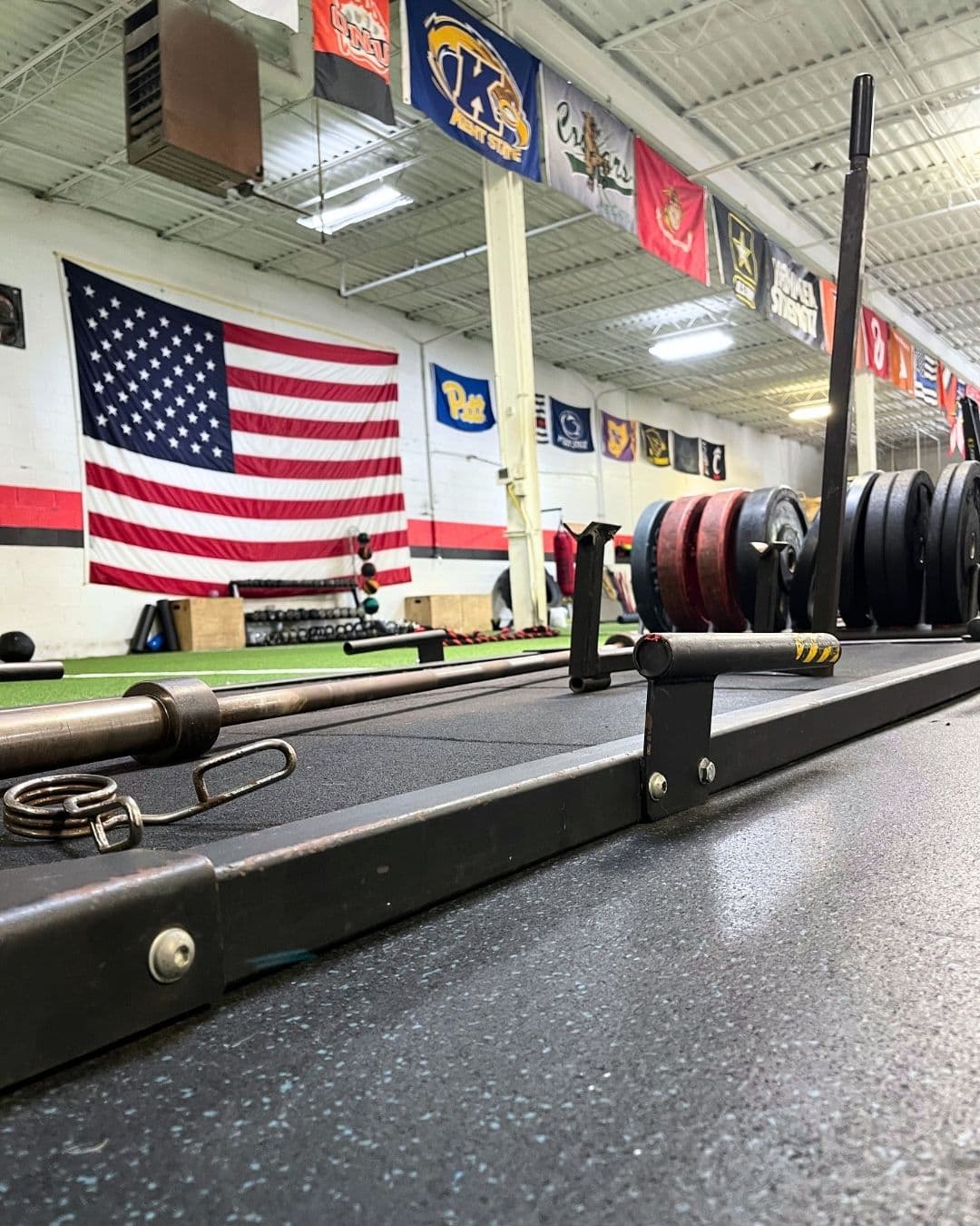 Barbell platform with American flag and college banners at AIM Performance Training in Mentor, Ohio